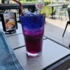 Eat Sight Story Deck on the Chao Phraya River overlooking Wat Arun. Bangkok, Thailand. July 2019. Butterfly pea flower mocktail
